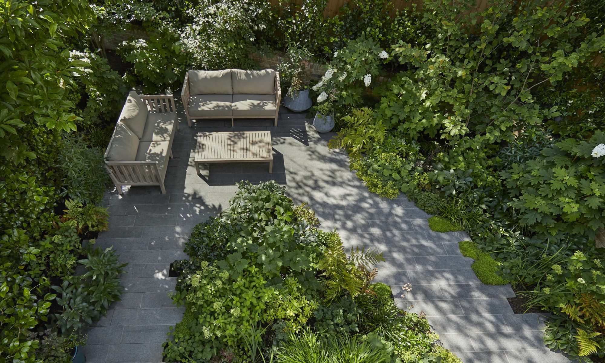 London garden by Shoots & Leaves seen from above, with a paved seating terrace surrounded by layered green planting